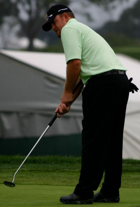 JB Holmes in a green t-shirt playing golf.